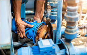 Technician adjusting valves on an industrial water-pump system – Bomba Plumbers water systems maintenance.