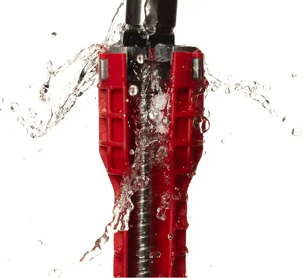 Burst pipe spraying water with a red pipe wrench – emergency plumbing repair by Bomba Plumbers.