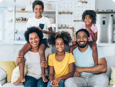 Happy family of five sitting together in a bright kitchen, representing satisfied Bomba Plumbers customers.